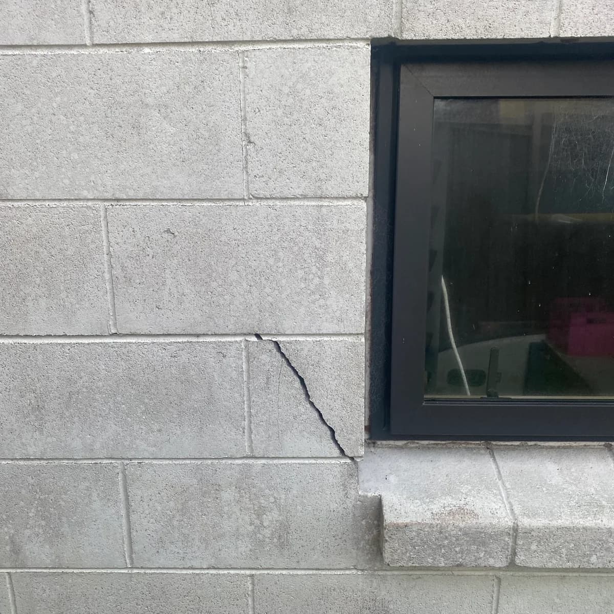 A foundation block crack beside a window, photographed for context
